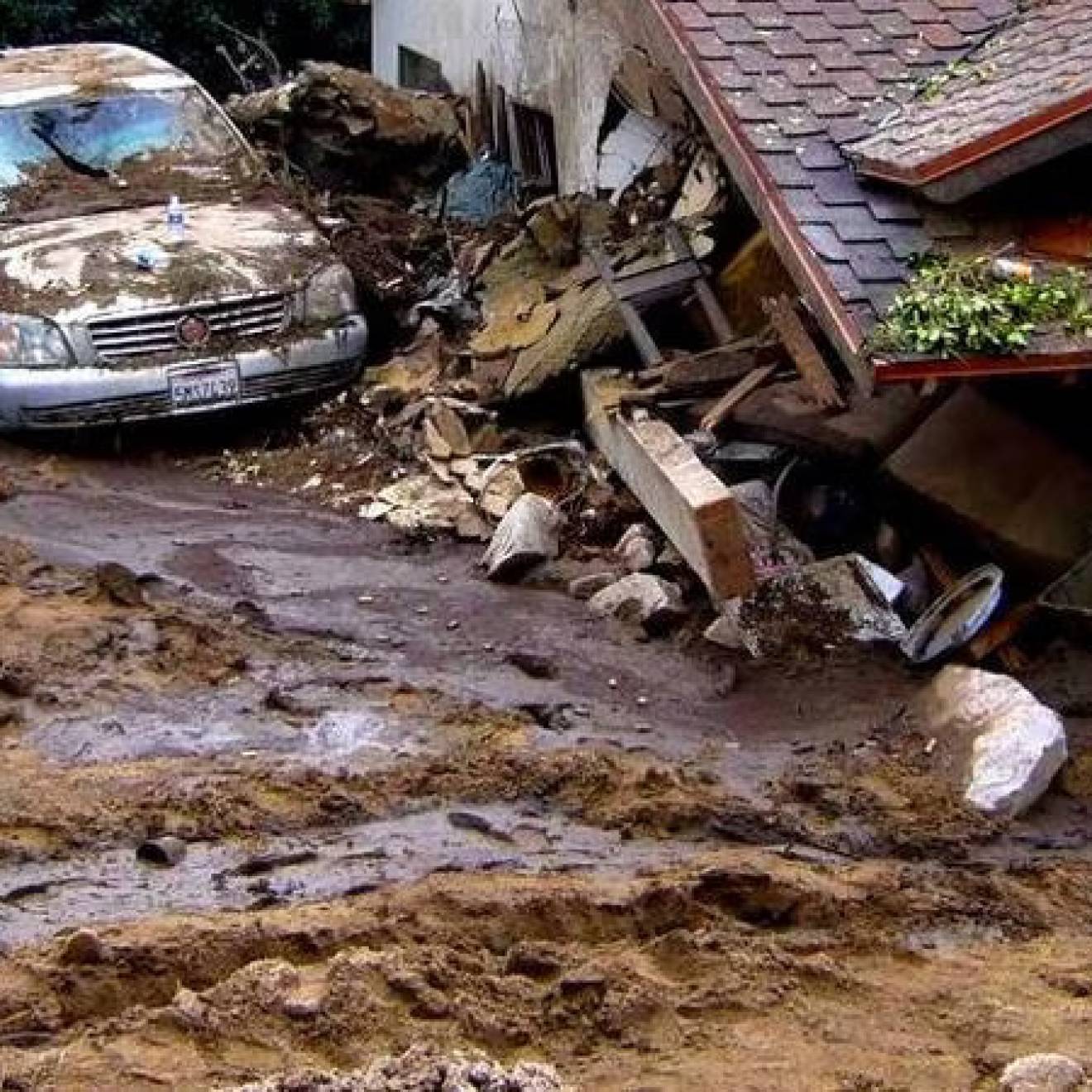 A car covered with mud and a house collapsed from a mudslide