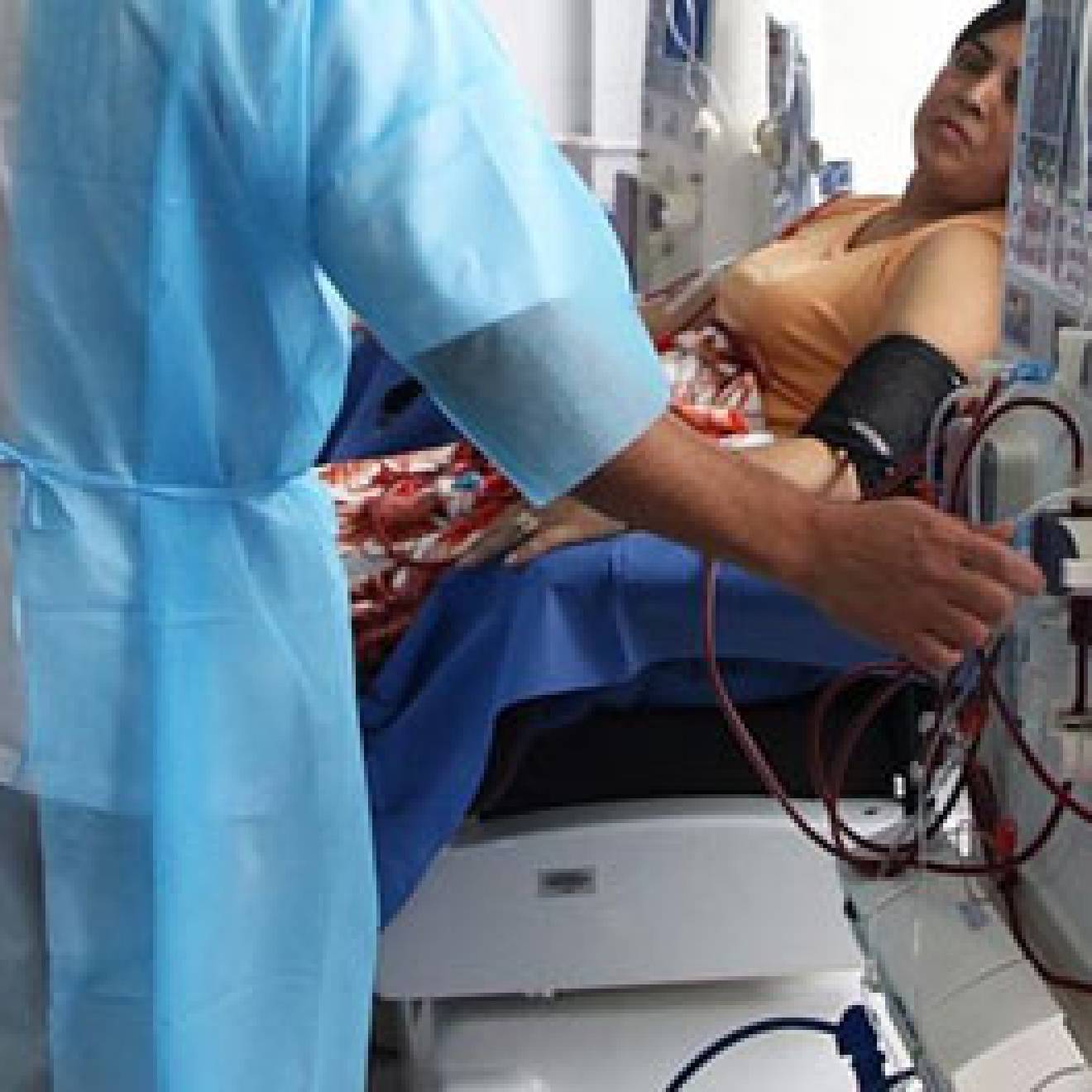 Nurse operating dialysis machine next to a woman