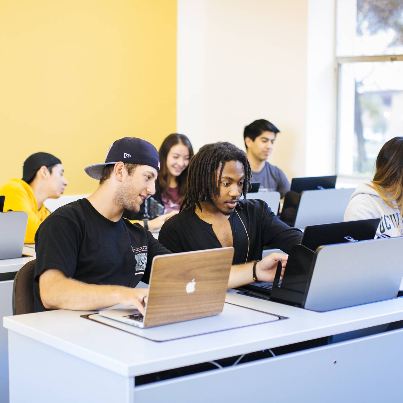 Diverse students looking at computers together in a classroom