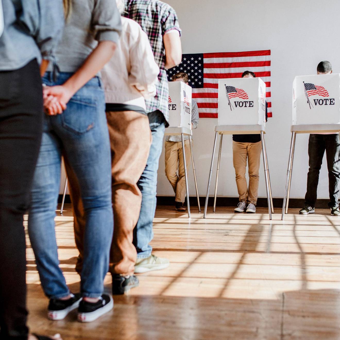 A line of people ready to vote and one person in a booth