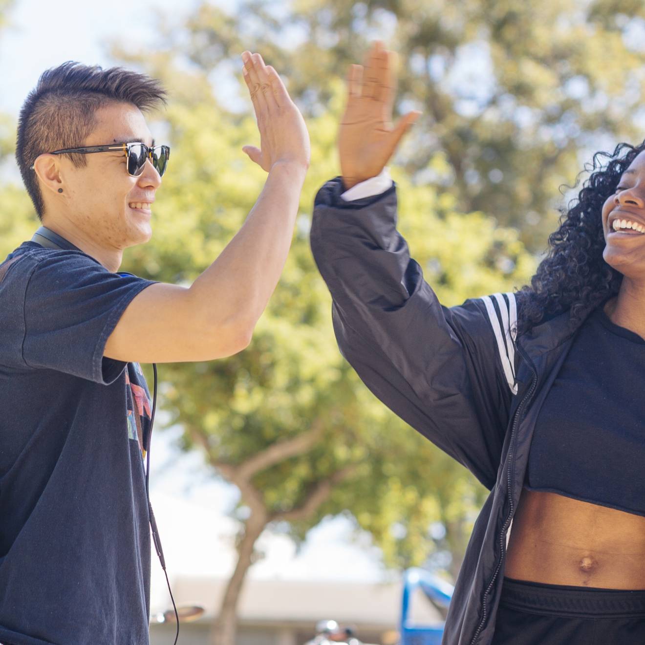 Two UC Davis students, a young Asian man and young Black woman, give each other a high five