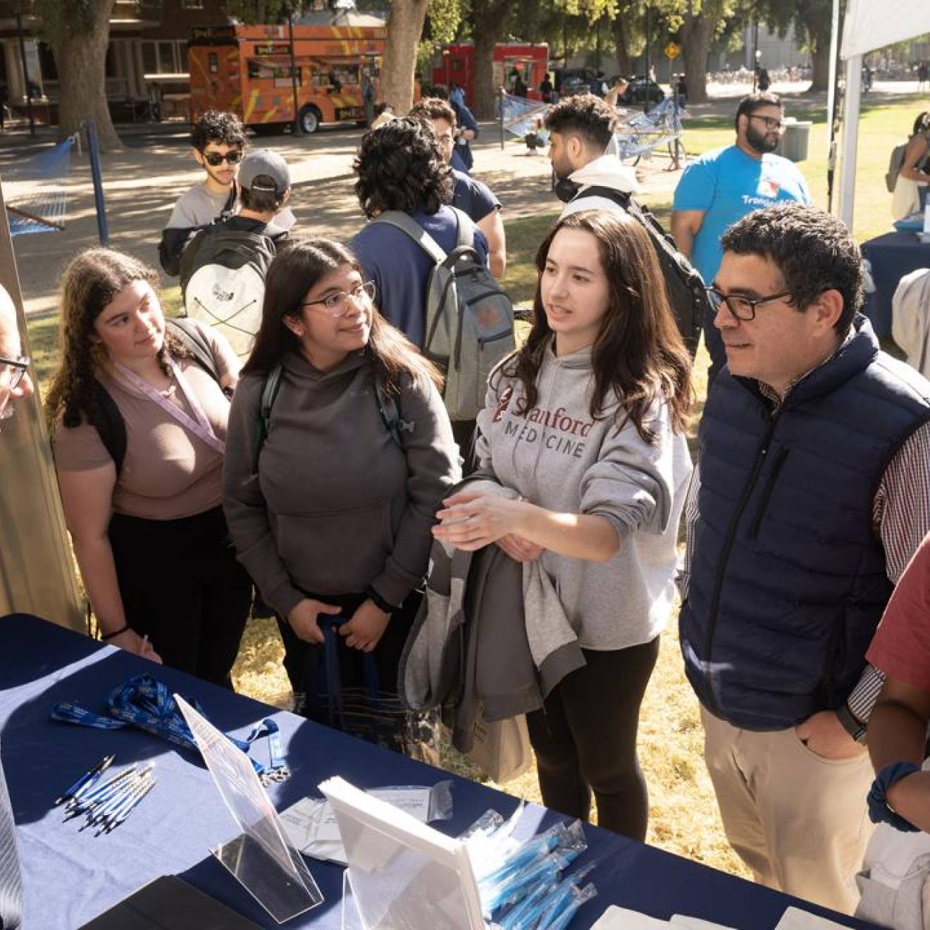 A number of undergraduates at a table outdoors during an event on campus