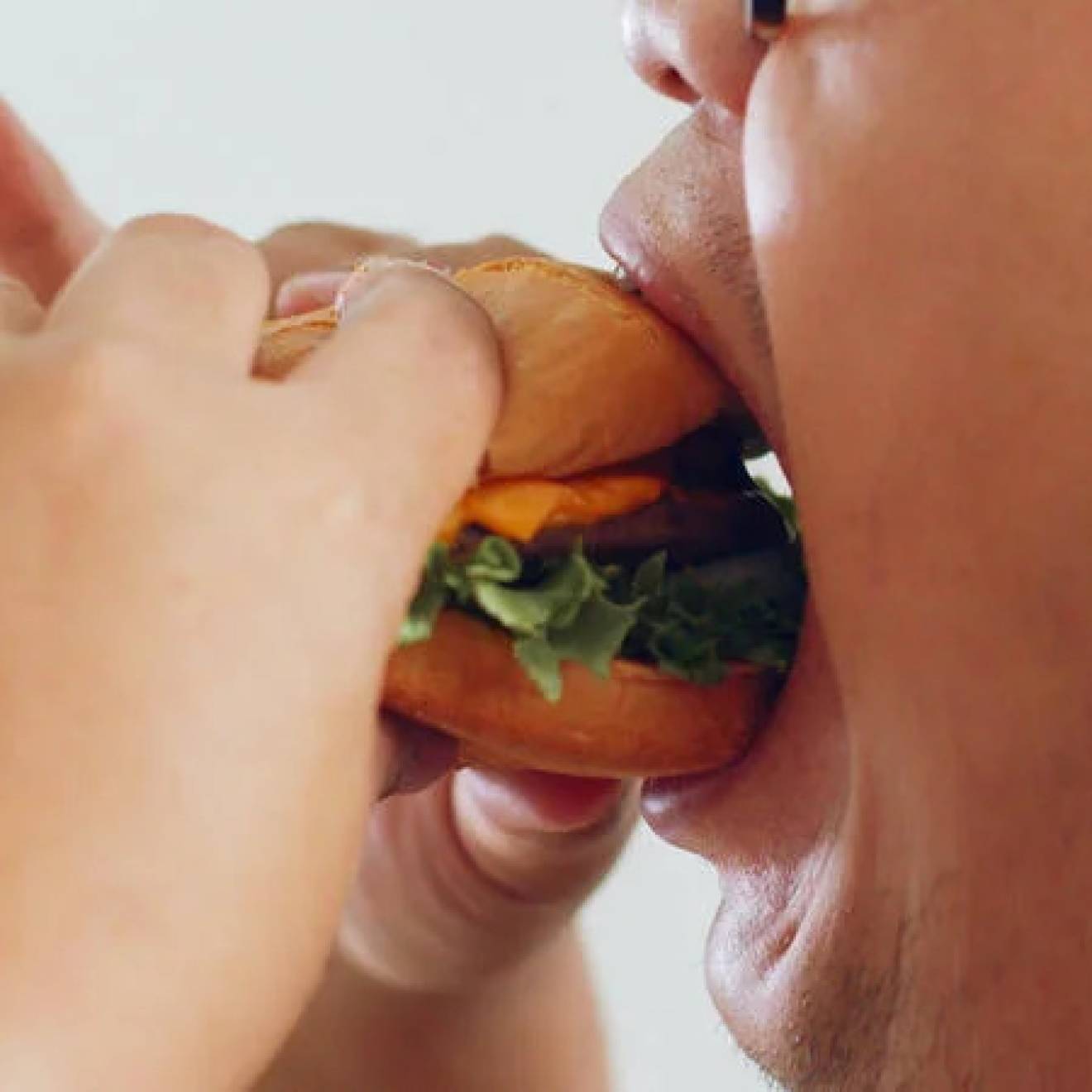 View of a man's mouth eating a burger dramatically