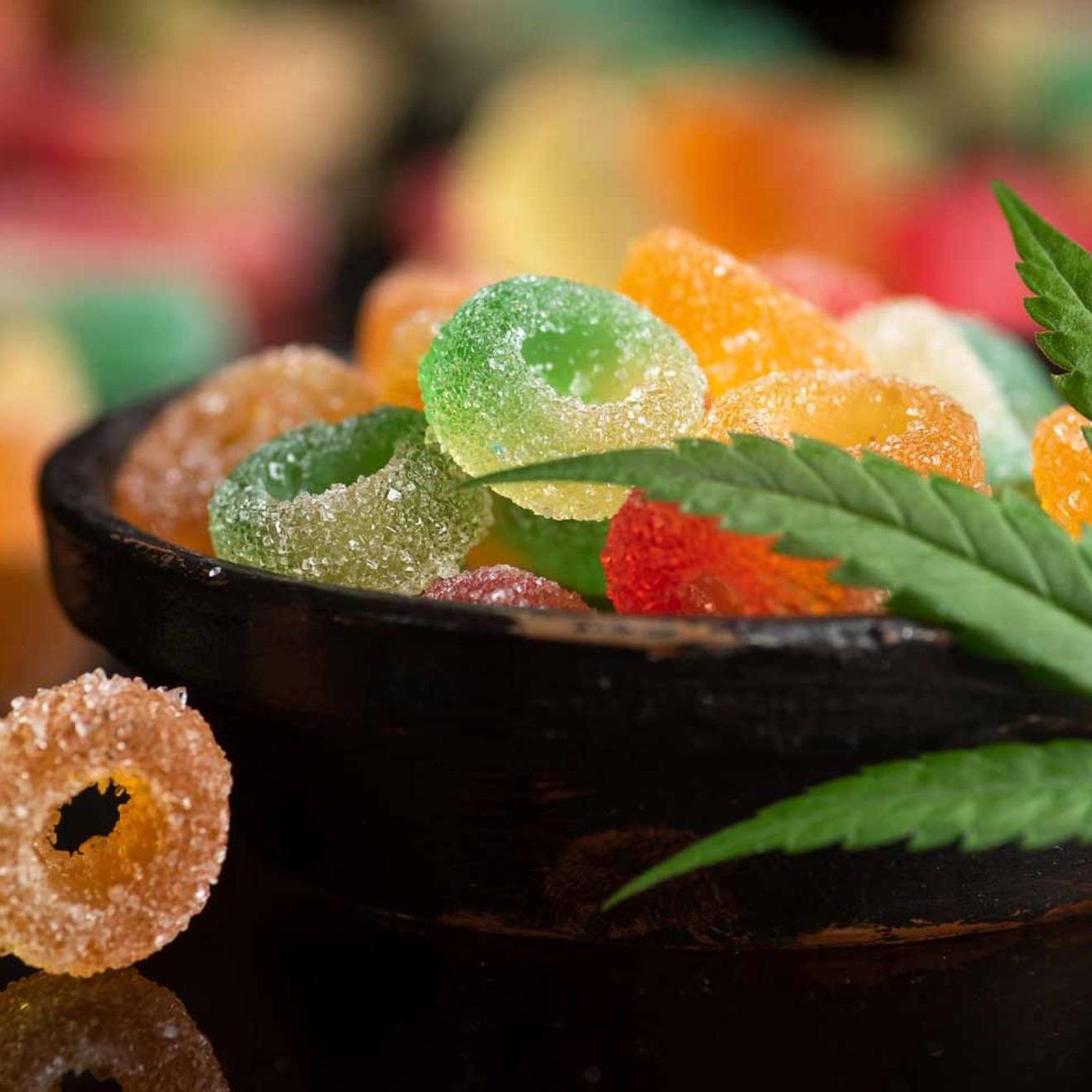 Gummies or edibles A bowl of gummies with a marijuana leaf draped over it