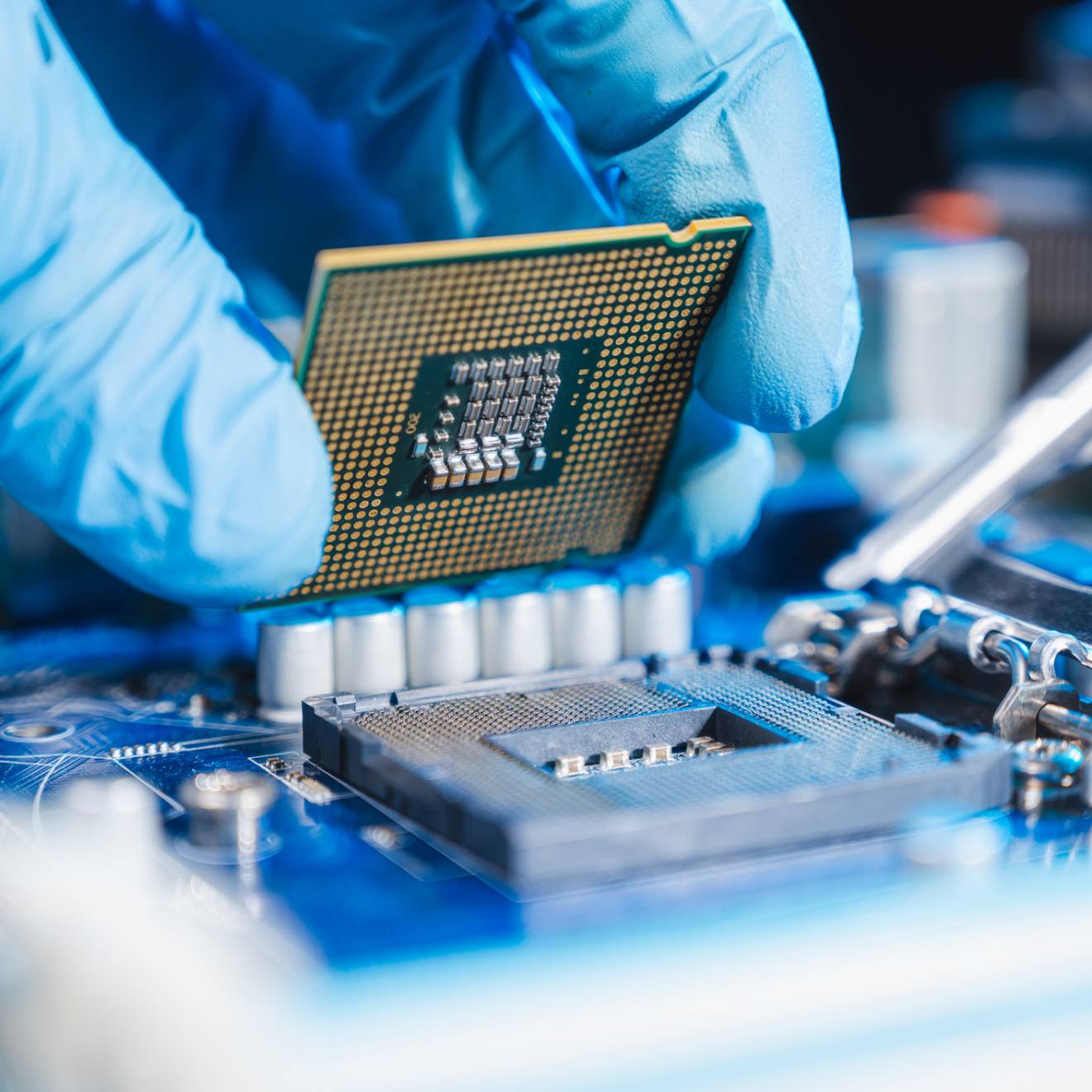 Close-up of a blue-gloved hand constructing a microchip