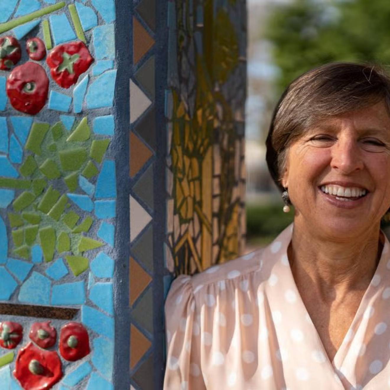 Flood-resistant rice earns prestigious prize Woman smiles next to an outdoor pillar with a tomato mosaic