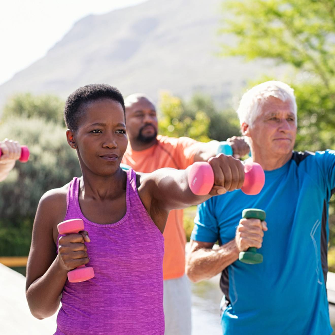 Older adults working out together with weights outdoors