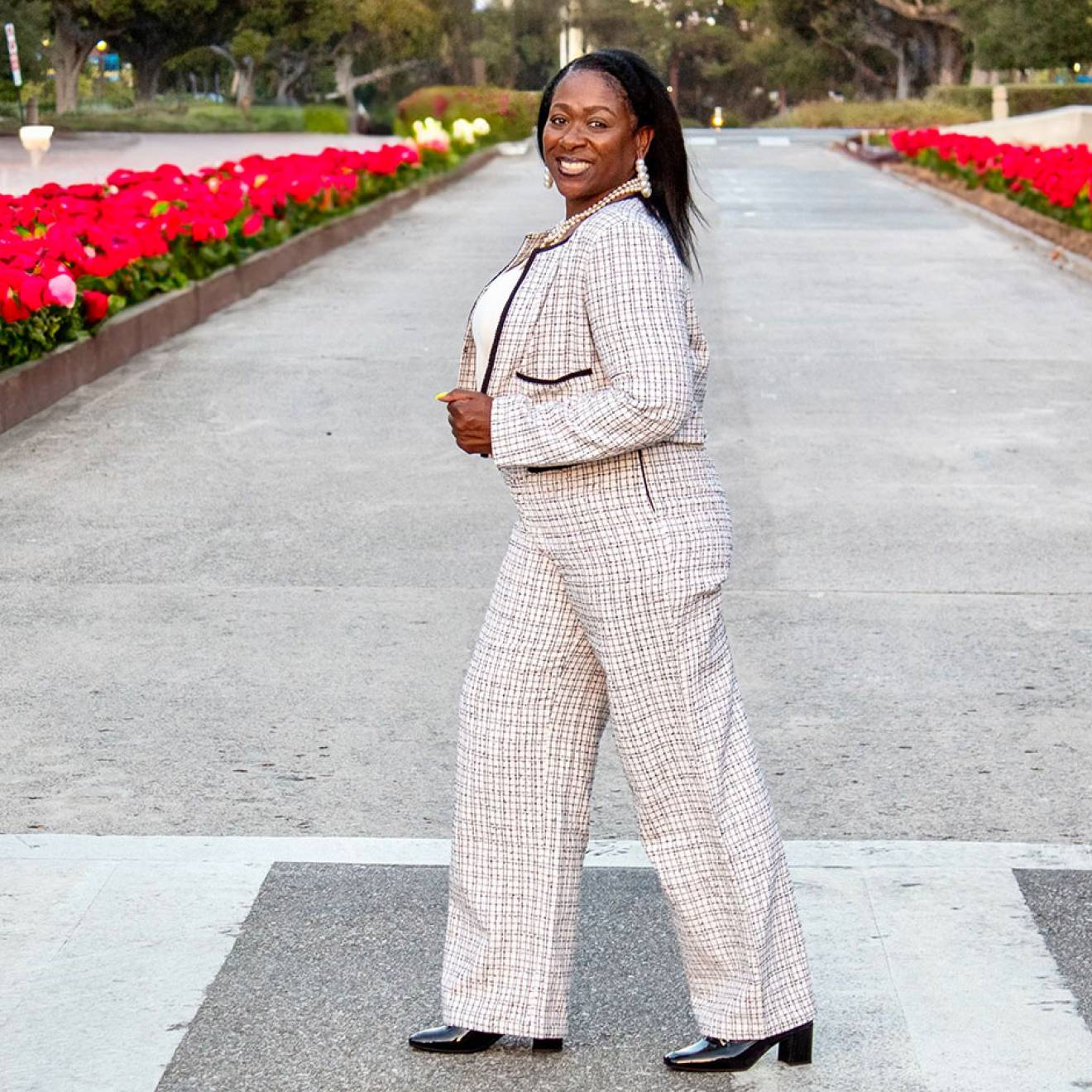 Sonya Brooks walks in a crosswalk across a street lined with red tulips