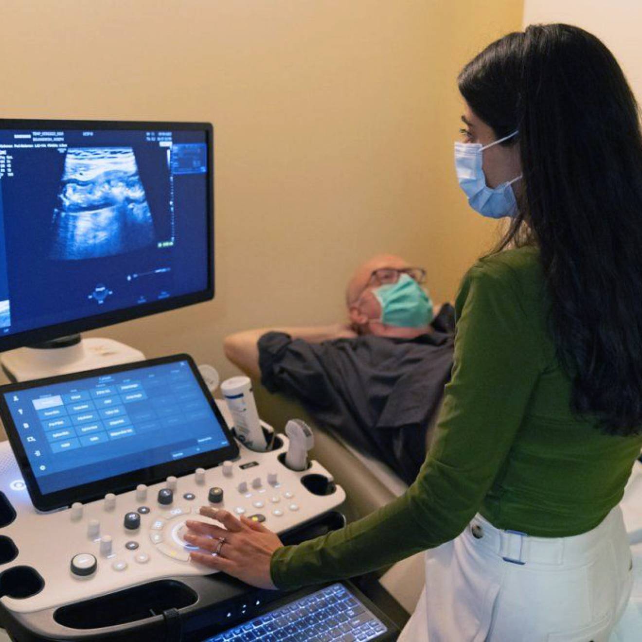 A doctor looking at a patient's ultrasound while the patient reclines nearby