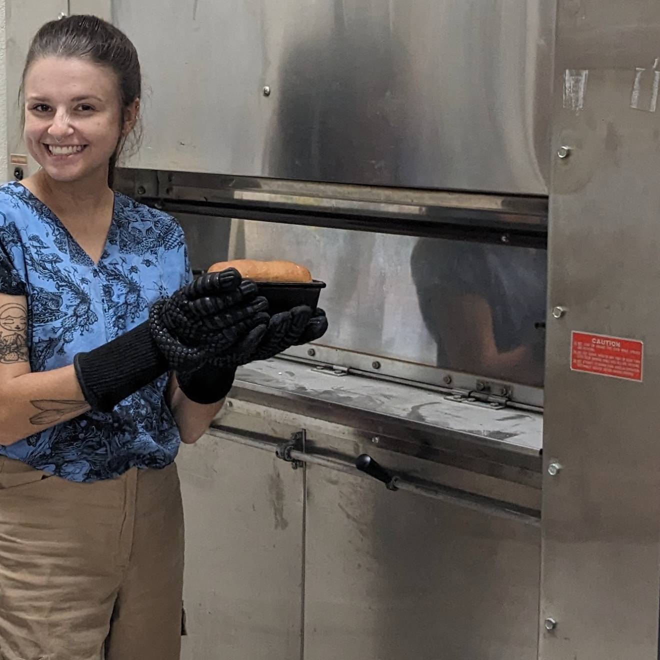 Protein-deleted wheat Woman with baking mitts smiles and holds up a loaf of bread in front of an oven