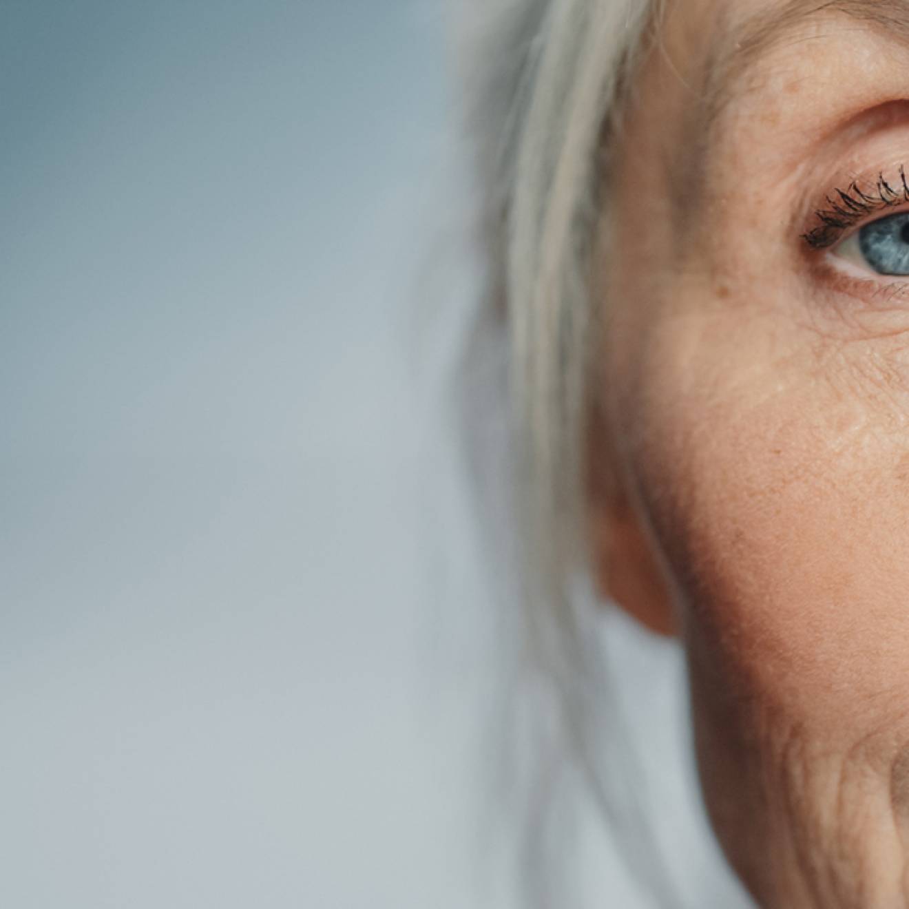 Senior woman with gray hair and blue eyes looking ahead straight at the camera