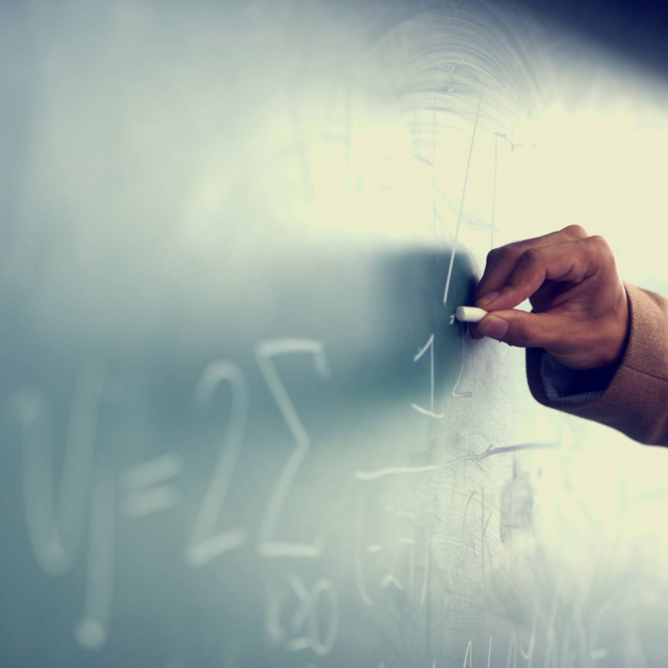 A Black teacher writing on a chalkboard