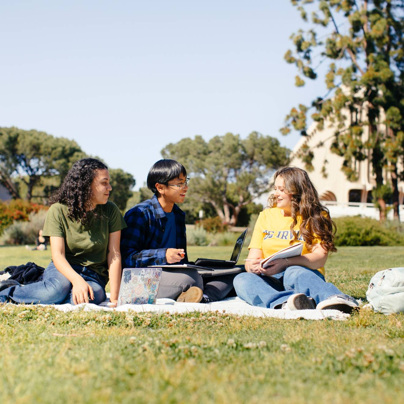 UC campuses are the country's best value, per two new rankings Three students on a picnic blanket studying talk to each other on the UC Irvine campus under a bright sky
