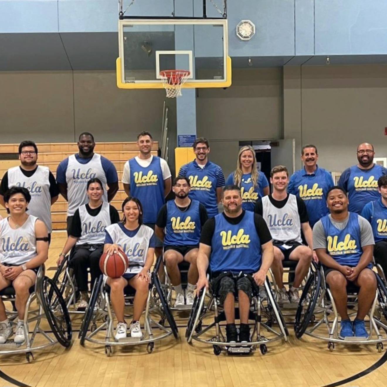 Group photo of the UCLA wheelchair basketball group in front of a basketball net