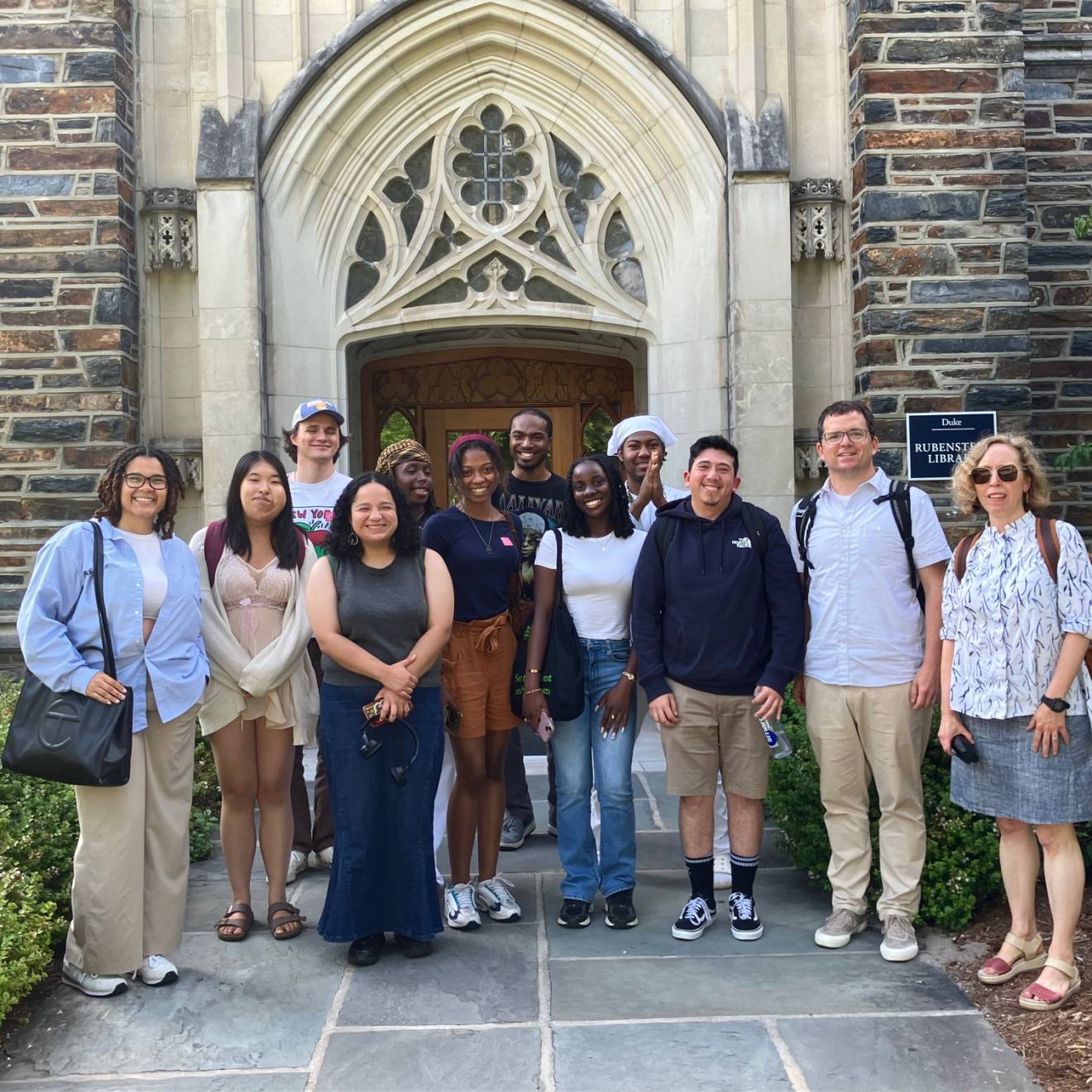 A group of people outside an old stone building with an arched entryway