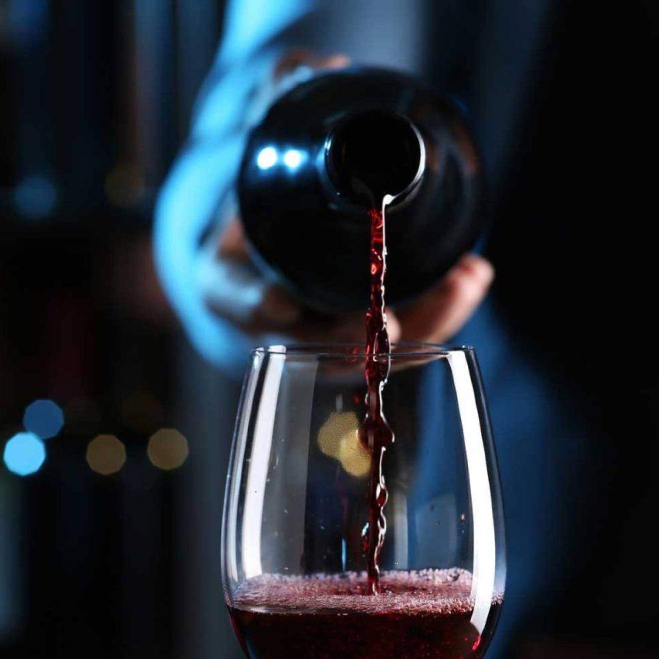Is there a healthy amount to drink A hand pours a bottle of red wine into a wine glass, centered