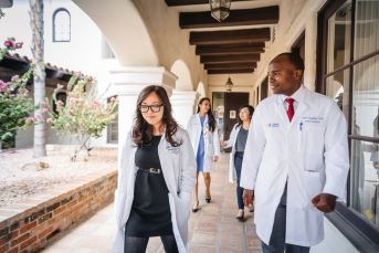 Image of University of California Health health professional students walking in outdoor courtyard.